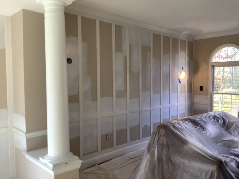 Room under renovation with patches of spackle on walls, a ladder, and a stone fireplace.