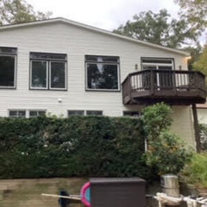 image shows the exterior of a two-story house with white siding and black-framed windows