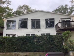 image shows the exterior of a two-story house with white siding and several windows