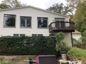 image shows the exterior of a house with white siding and dark-framed windows