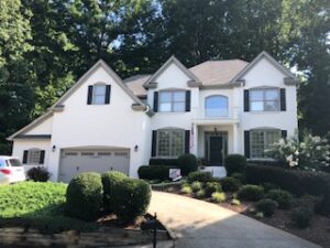 image shows a two-story house with a light-colored exterior