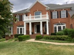 image shows the exterior of a large, two-story, and red brick house