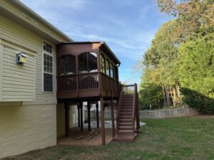 image shows the exterior of a house with a screened-in porch and a set of stairs leading down to the yard